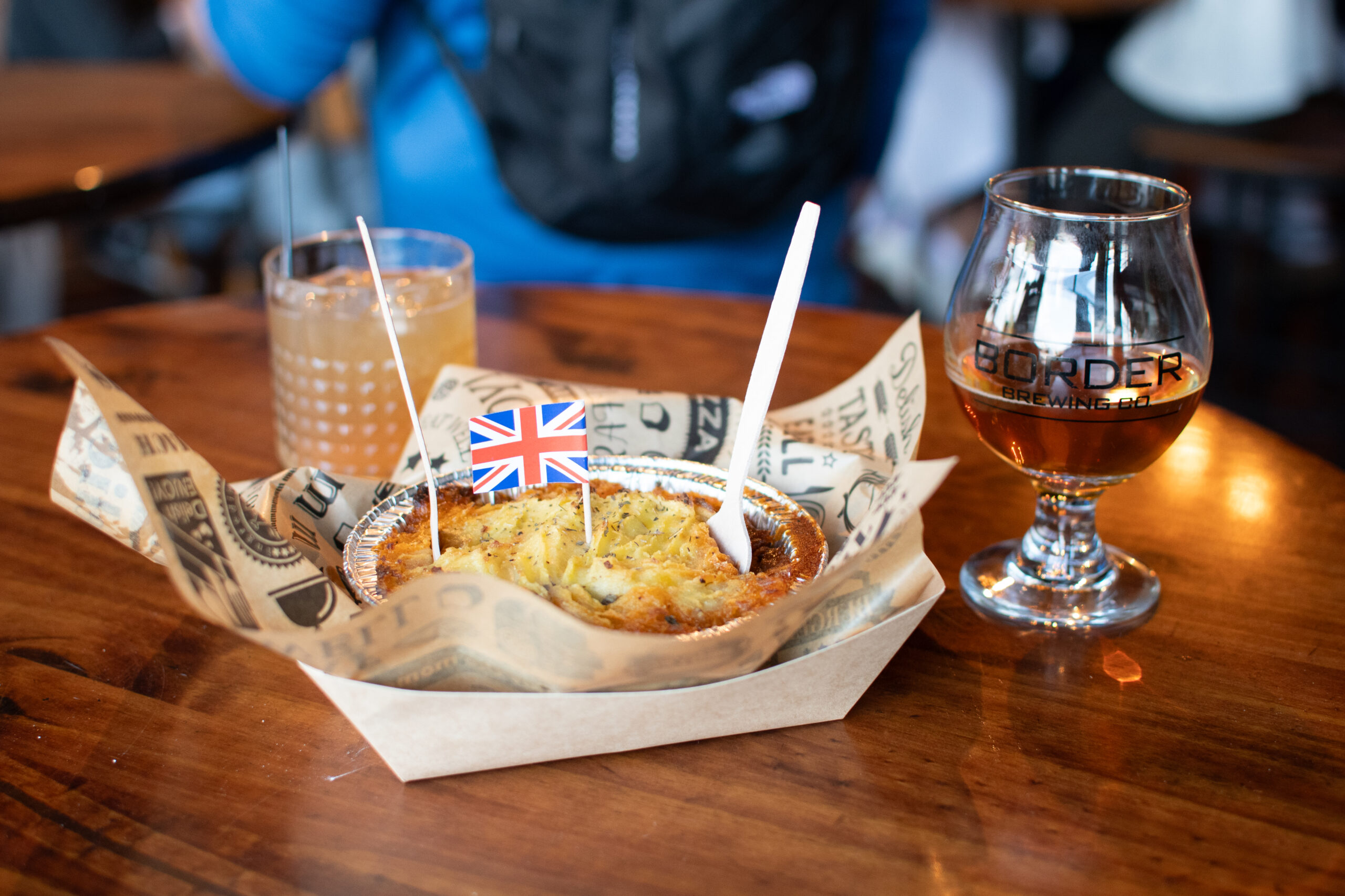 Brit Boy Street Food pie hot and ready with a beer and cocktail beside on a wooden bar in KC