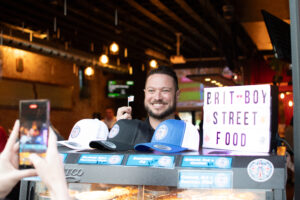 Chris Thomas, owner of Brit Boy Street Food holding a mini British flag at a pop up in KC